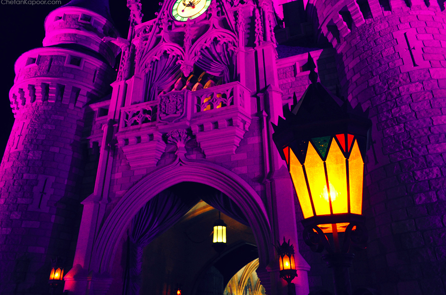 紫のライトでライトアップされるシンデレラ城の写真